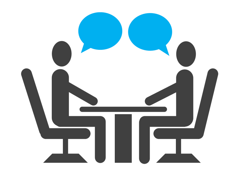 Entraînement personnalisé à la tenue d'un entretien d'embauche Deux personnes discutent autour d'une table avec des bulles de dialogue.