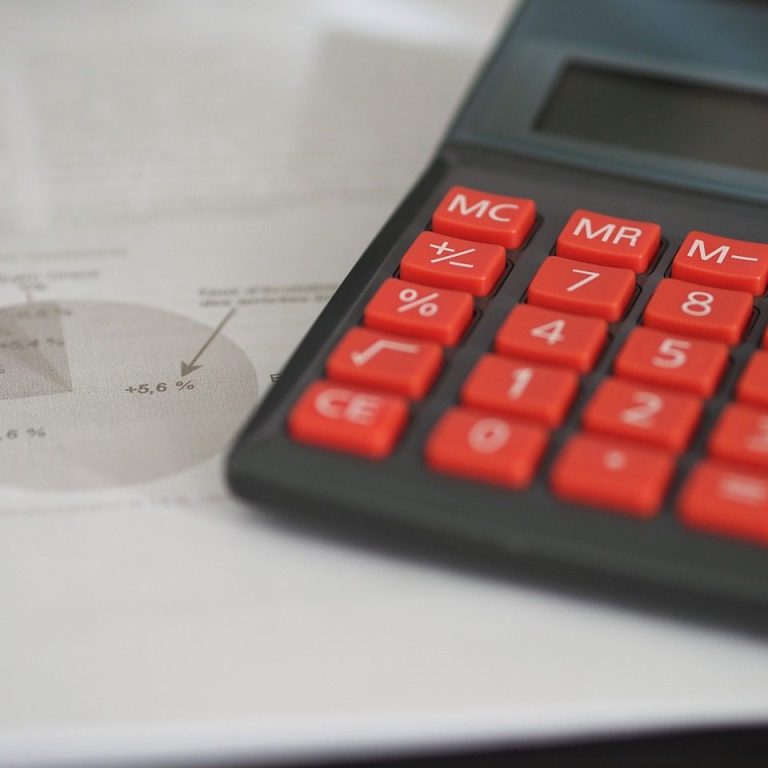 Accompagnement en gestion d'entreprise Calculatrice avec touches rouges et document avec graphique en arrière-plan.